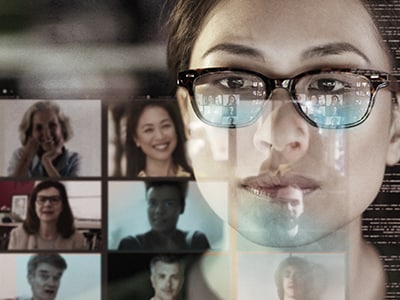 Representing the hybrid workforce with an image of a woman's face reflected in a computer screen, superimposed over tiles from a video call.