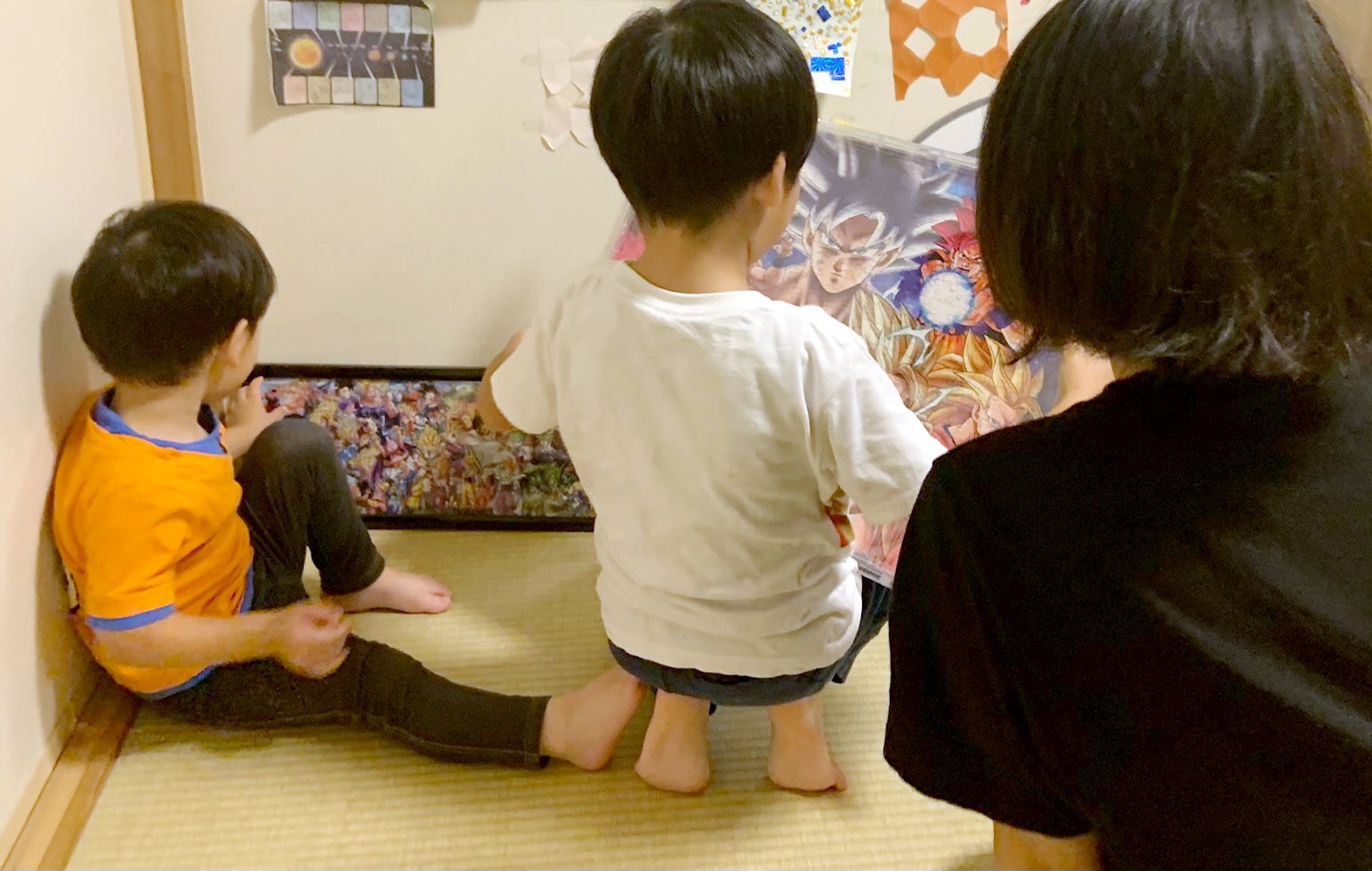 this is a picture of a mother and two kids, trying to solve a board of puzzle.