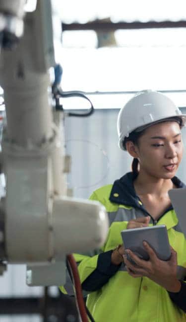 Two people wearing hard hats and looking at a computer